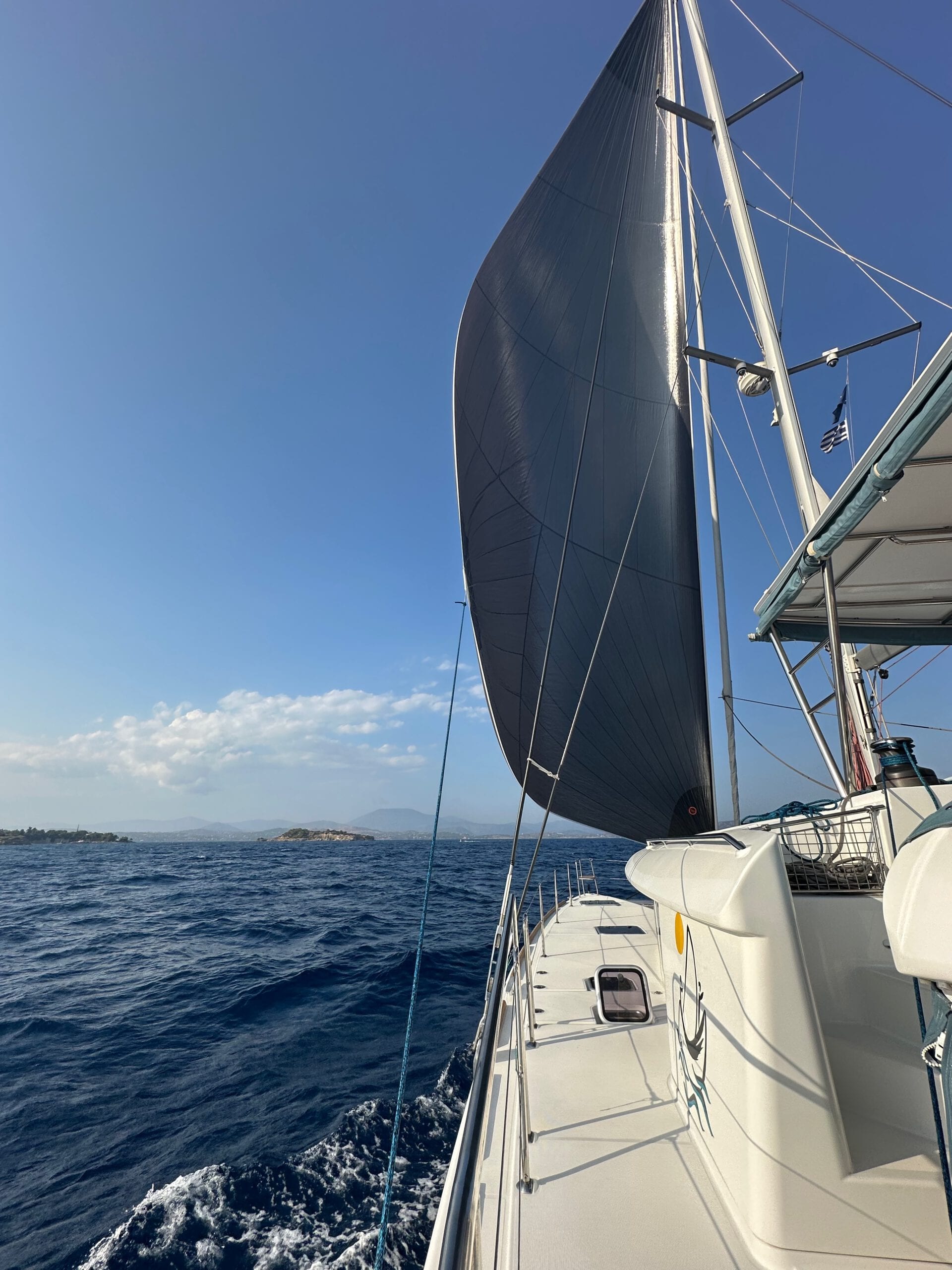 Die MyWay unter Spinnaker, Blick auf eine kleine Insel und die küstennahen Berge der Argolis.